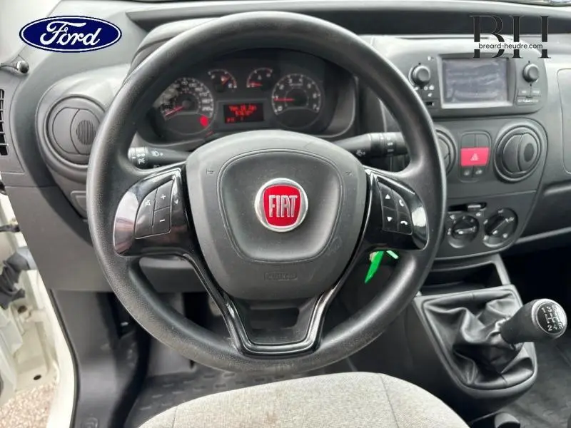 Vue intérieure centrée sur le volant multifonction noir avec logo Fiat rouge, tableau de bord et levier de vitesse manuel.
