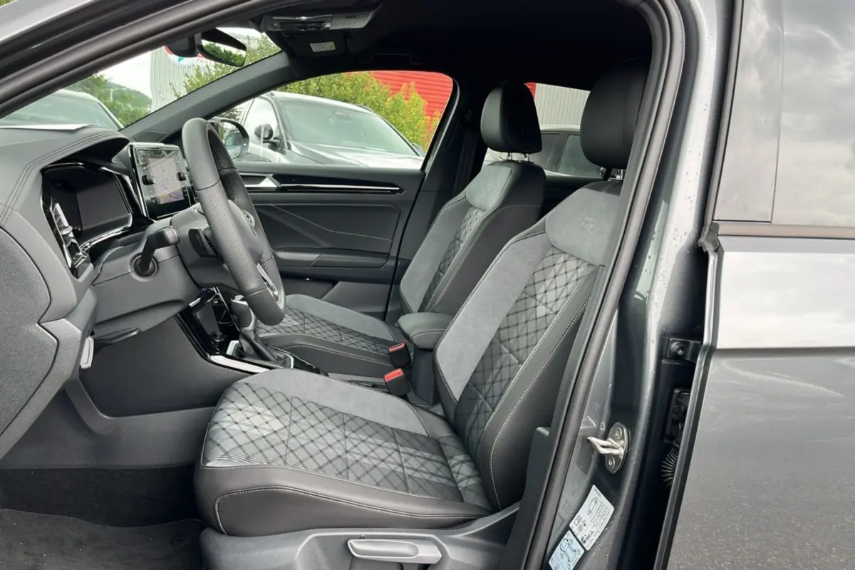 Vue intérieure côté conducteur du Volkswagen T-Roc gris indium 2025, mettant en valeur les sièges R-Line Black en cuir et alcantara.