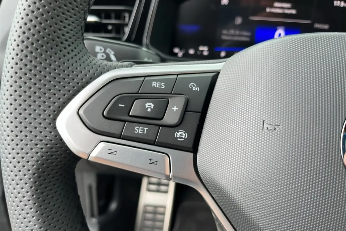Gros plan sur le volant perforé gris du Volkswagen T-Roc 2025 R-Line Black avec commandes de régulateur de vitesse.