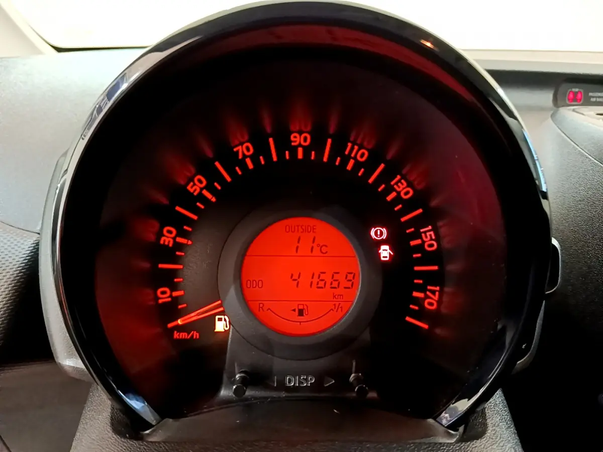 Vue rapprochée du compteur de vitesse rouge éclairé de la Citroën C1 blanche, affichant 41669 km et 11°C extérieur.