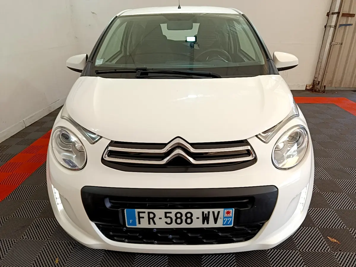 Vue avant d'une Citroën C1 blanche 2020 avec feux LED et calandre noire dans un garage.