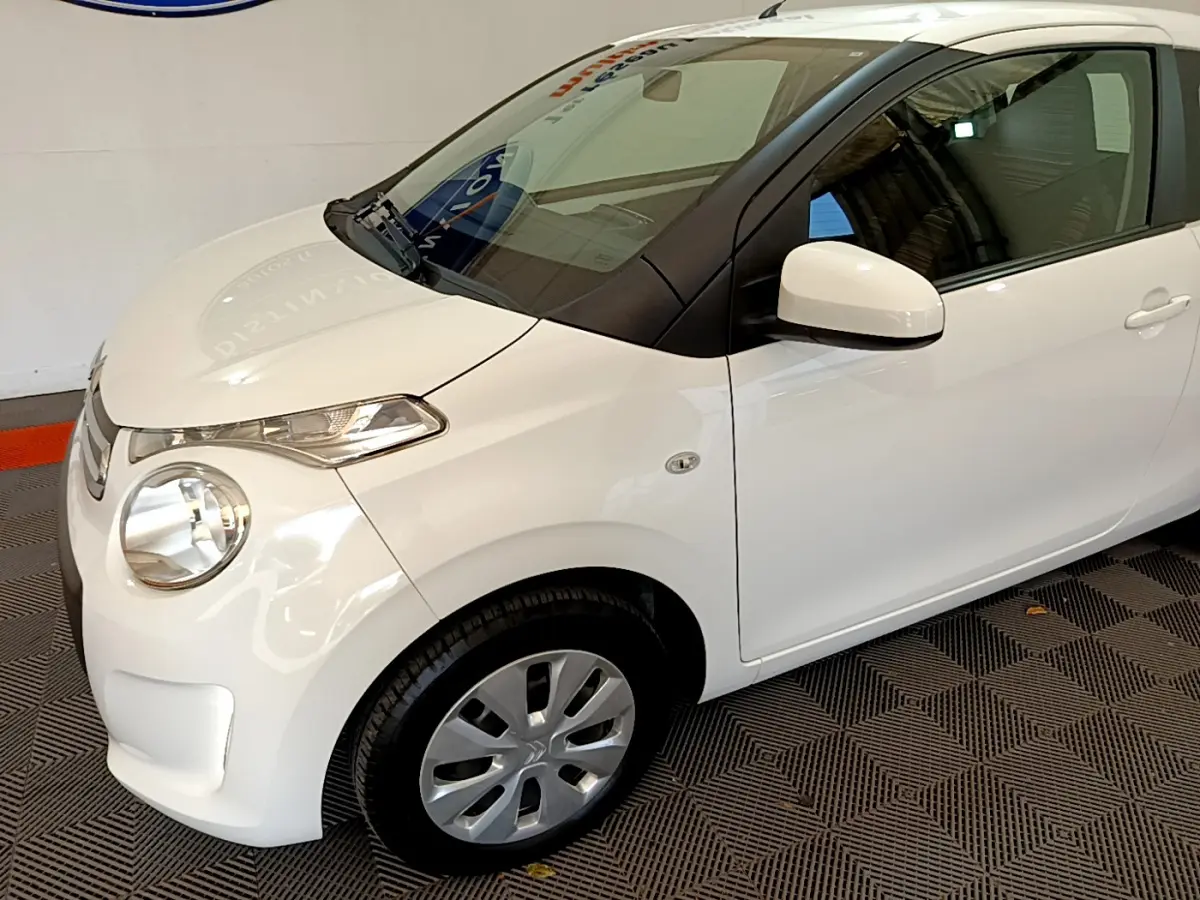 Vue 3/4 avant droit d'une Citroën C1 blanche 2020 avec rétroviseurs assortis et jantes acier.