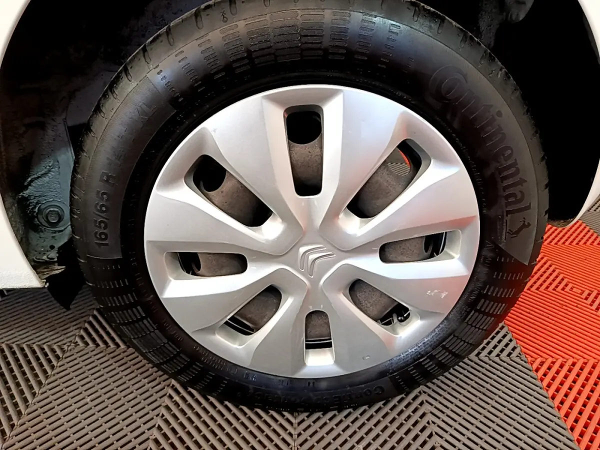 Gros plan sur la roue avant droite d'une Citroën C1 blanche avec enjoliveur argenté et pneu Continental.