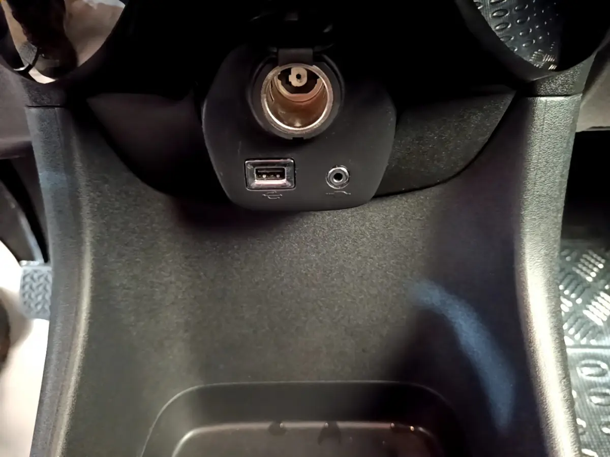 Vue rapprochée de la prise 12V, port USB et entrée audio dans l’habitacle de la Citroën C1 blanche de 2020.