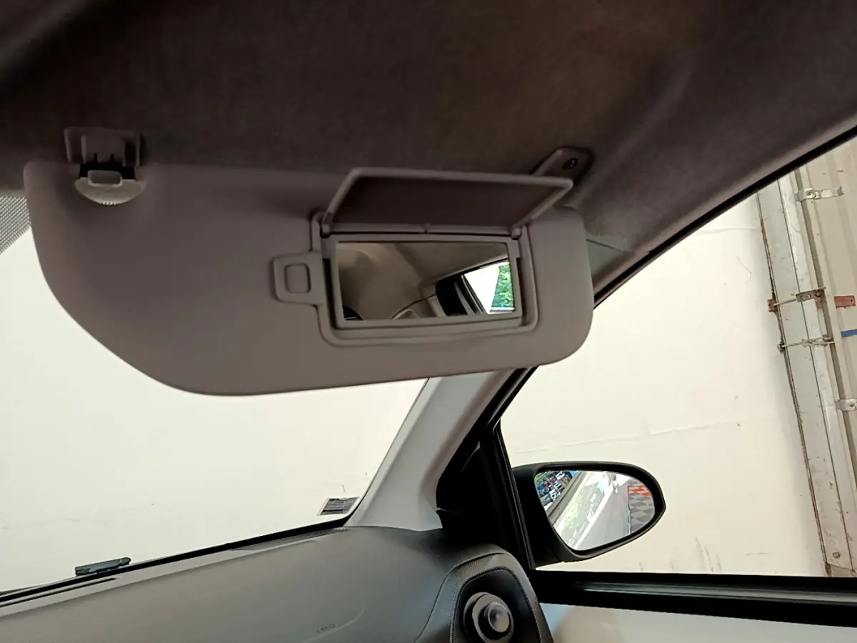 Détail intérieur du pare-soleil avec miroir ouvert côté conducteur d'une Citroën C1 blanche, vue vers la portière.