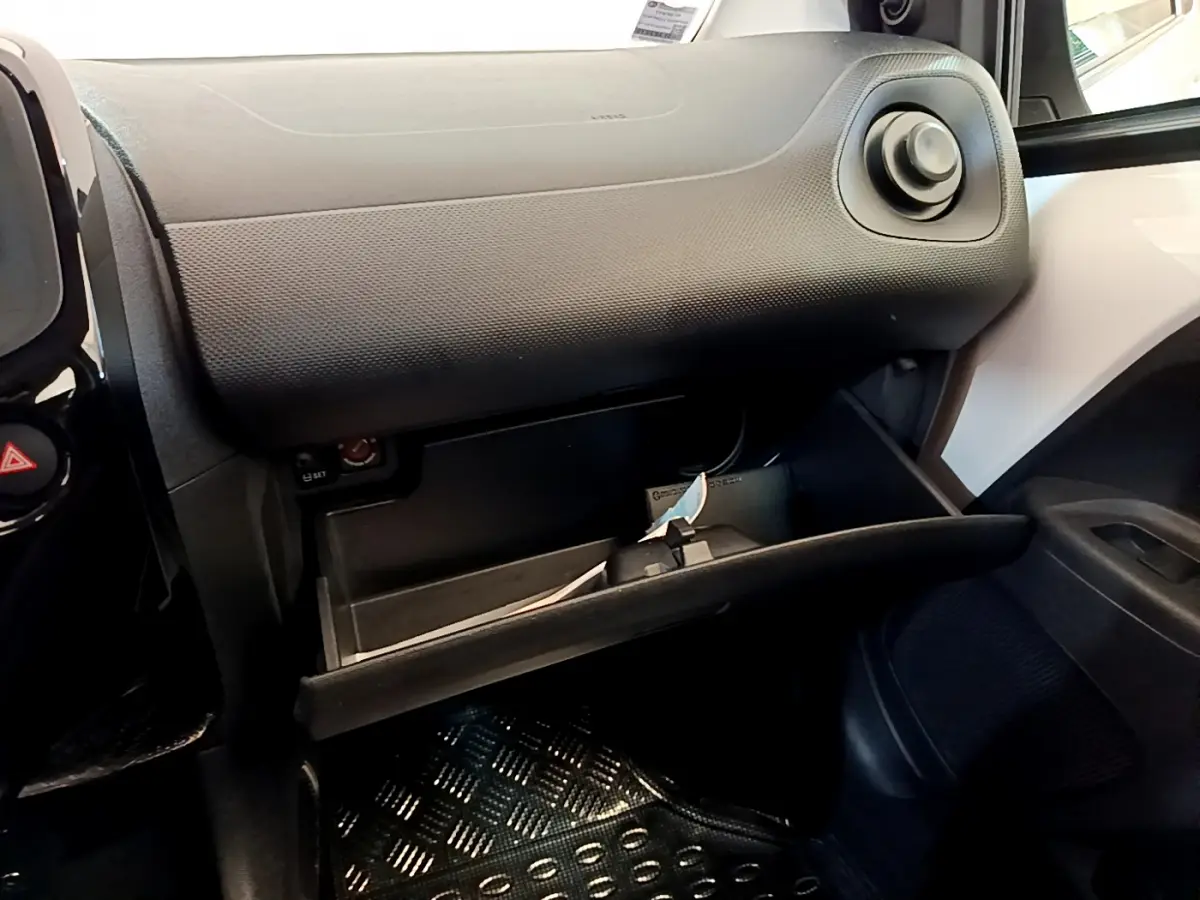 Vue intérieure côté passager du coffre à gants ouvert dans une Citroën C1 blanche, tableau de bord noir texturé visible.