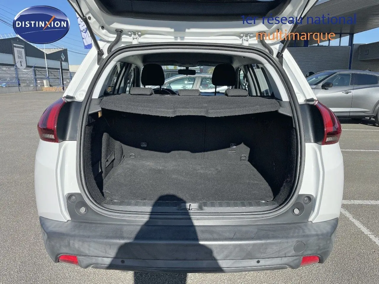 Coffre ouvert d'un Peugeot 2008 blanc vu de l'arrière, montrant l'espace de chargement et la banquette arrière.