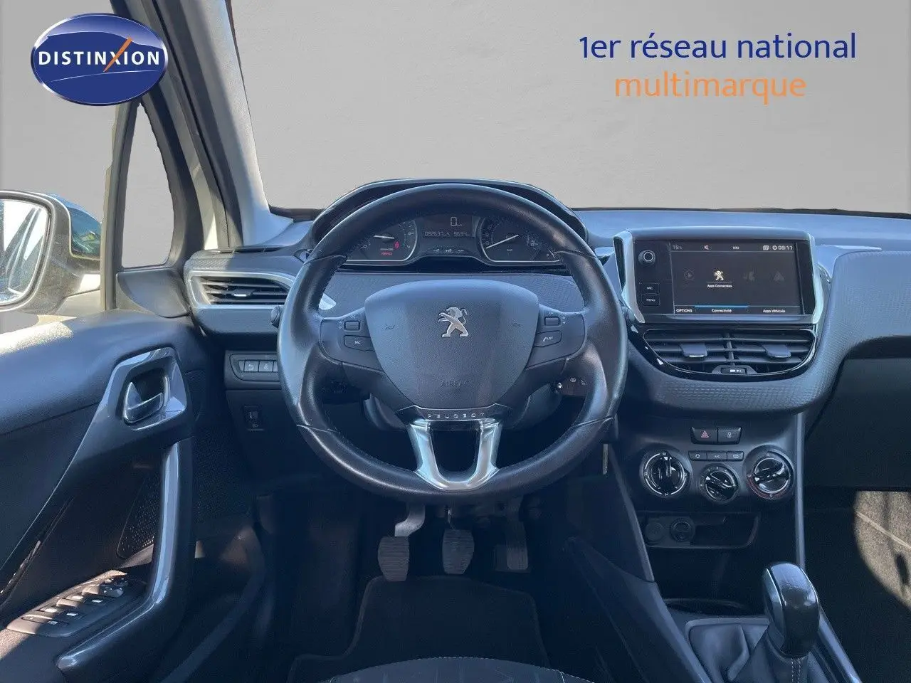 Vue intérieure frontale du tableau de bord et volant noir de la Peugeot 2008 blanche, avec écran tactile et commandes manuelles.