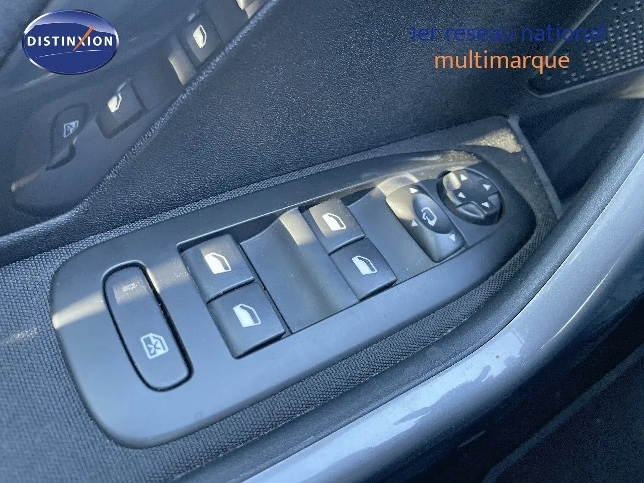 Gros plan sur les commandes des vitres électriques côté gauche d'une Peugeot 2008 blanche, version 2017.