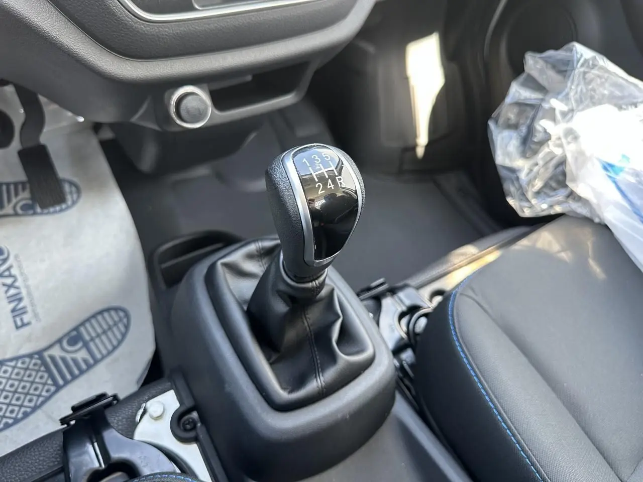 Le levier de vitesses manuel noir du Piaggio Porter 2024, vu en gros plan côté conducteur avec siège gris.