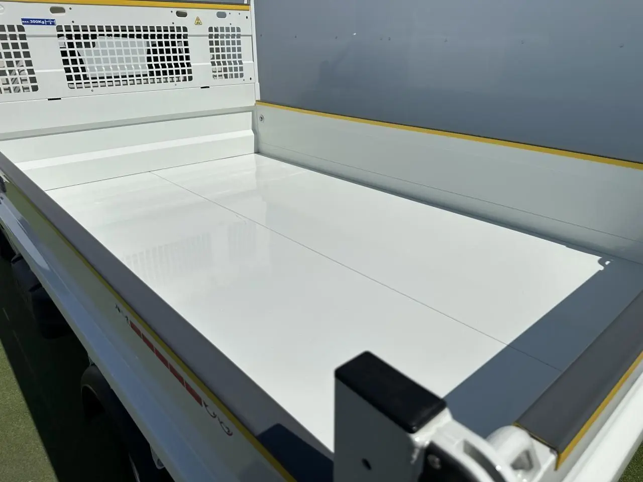 Vue en plongée sur la benne blanche du Piaggio Porter NP6 SWB, soulignant sa surface lisse et ses protections latérales.