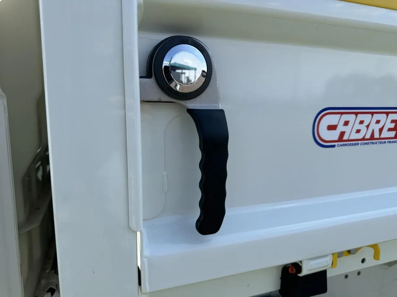 Poignée de benne blanche du Piaggio Porter 2024 vue de près, avec logo Cabreta visible sur la tôle.