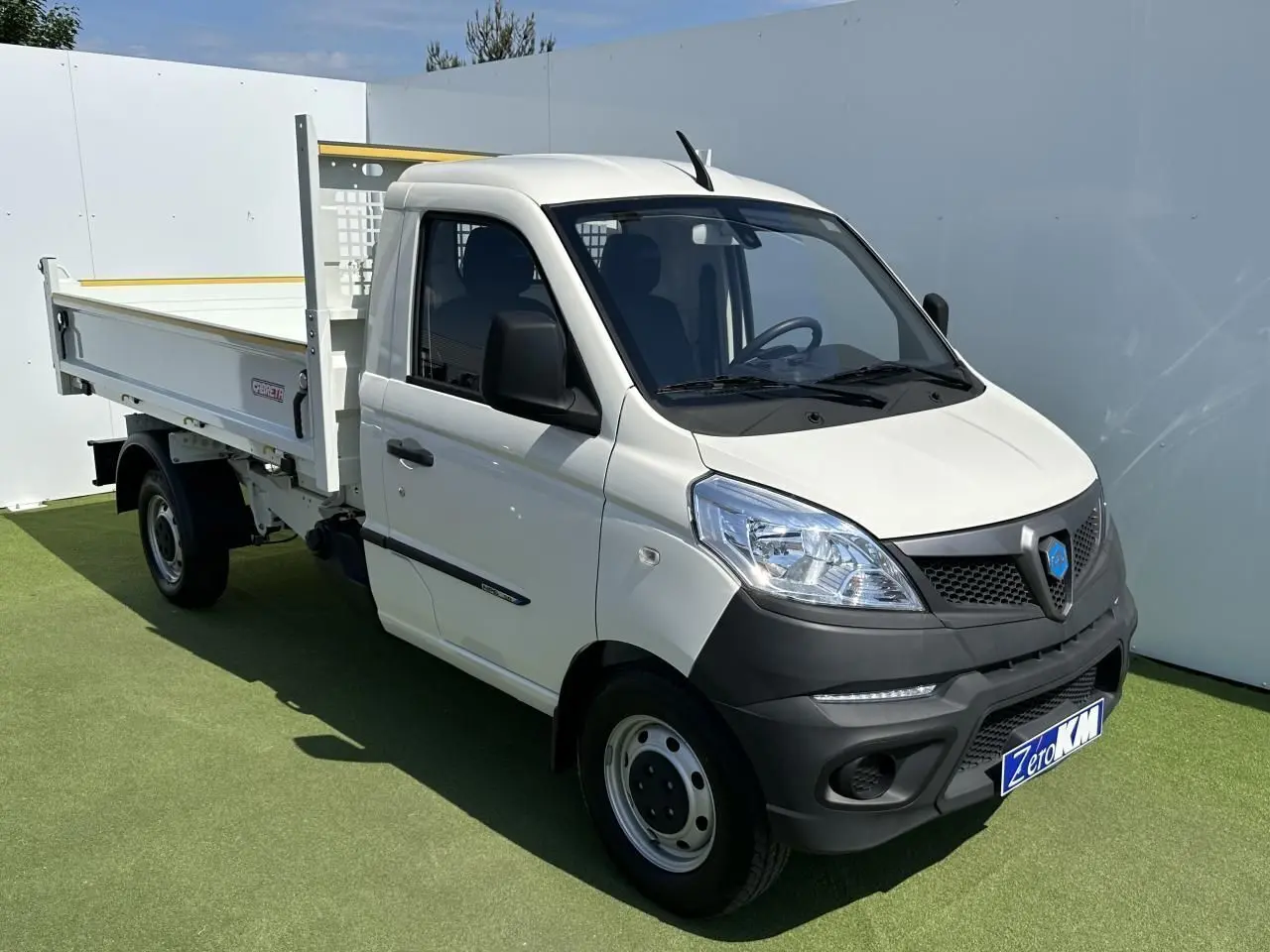 Petit utilitaire Piaggio Porter blanc vu en 3/4 avant droit avec benne longue et pare-chocs noirs contrastants.