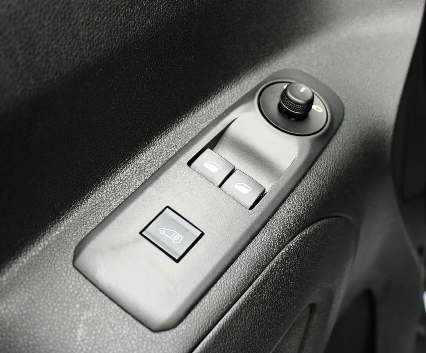 Gros plan sur les commandes de lève-vitres et rétroviseurs sur la porte intérieure noire du Peugeot Partner Fourgon blanc 2025.