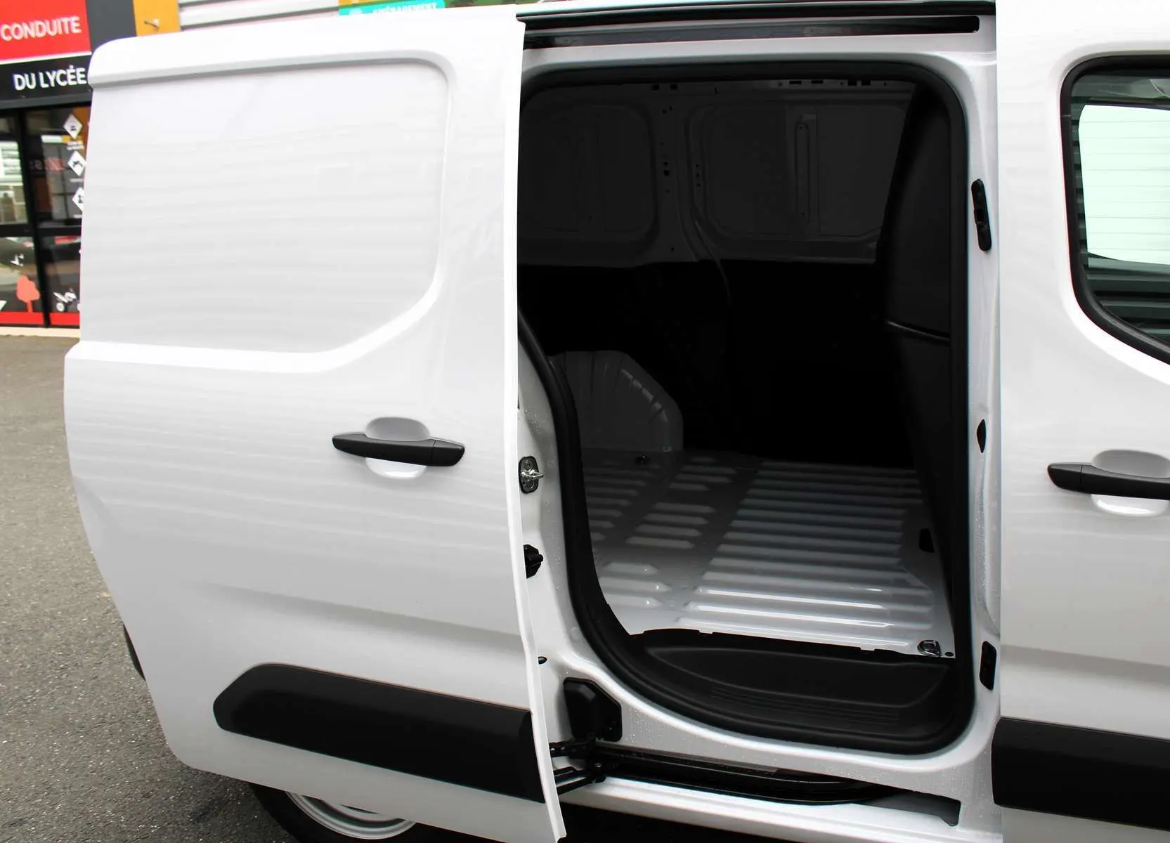 Vue latérale gauche du Peugeot Partner Fourgon blanc 2025 avec porte coulissante ouverte sur l'espace de chargement vide.