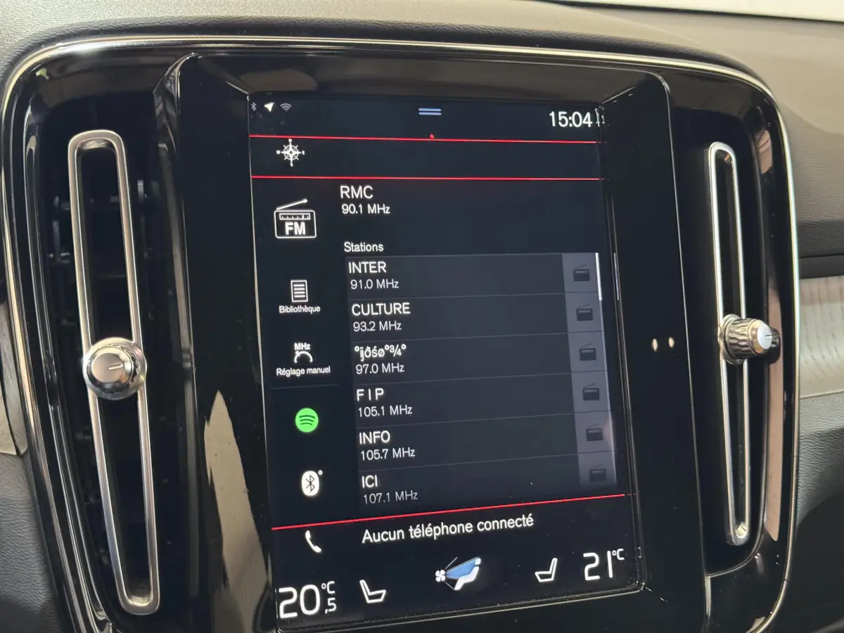 Écran tactile central du tableau de bord du Volvo XC40 noir, affichant les stations radio FM.
