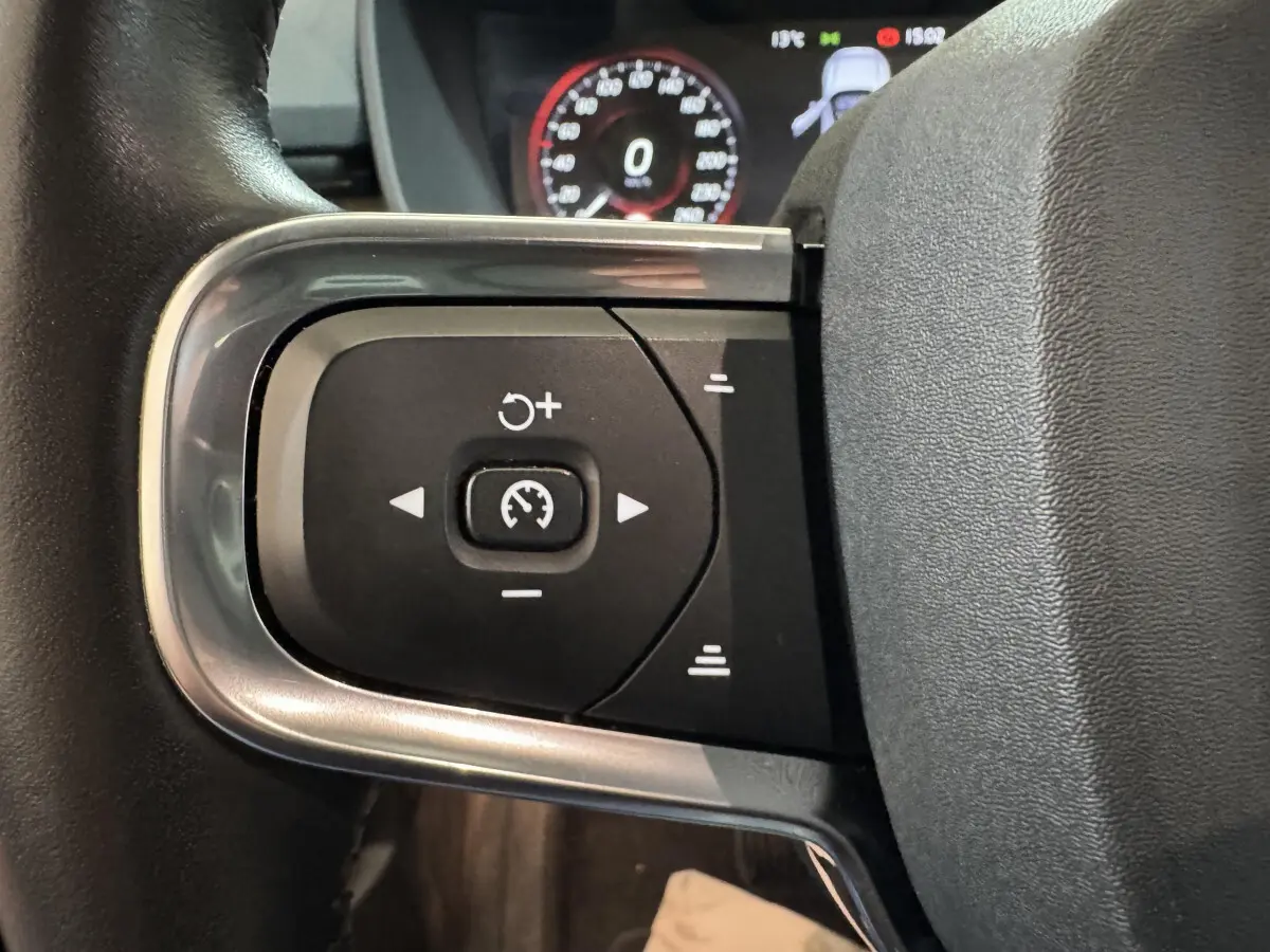 Gros plan sur les commandes de régulateur de vitesse au volant cuir noir du Volvo XC40 Recharge T5 2021.