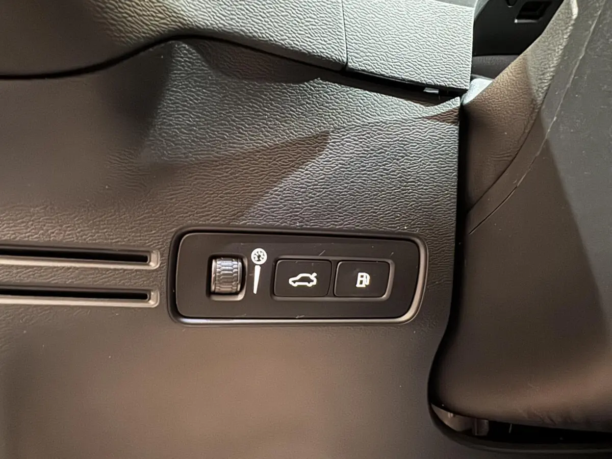 Gros plan sur les commandes d'ouverture du coffre et de la trappe à carburant du Volvo XC40 noir, intérieur côté conducteur.