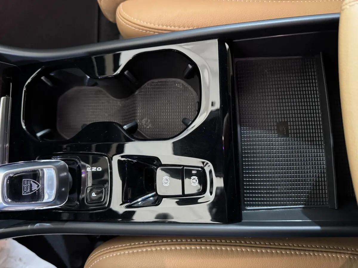 Vue rapprochée de la console centrale noire et beige du Volvo XC40 Recharge T5 avec levier de vitesse et porte-gobelets.