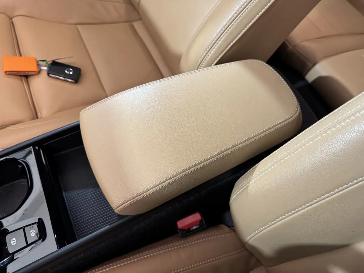 Vue rapprochée de l'accoudoir central beige et des sièges en cuir marron clair du Volvo XC40 Recharge T5 2021.