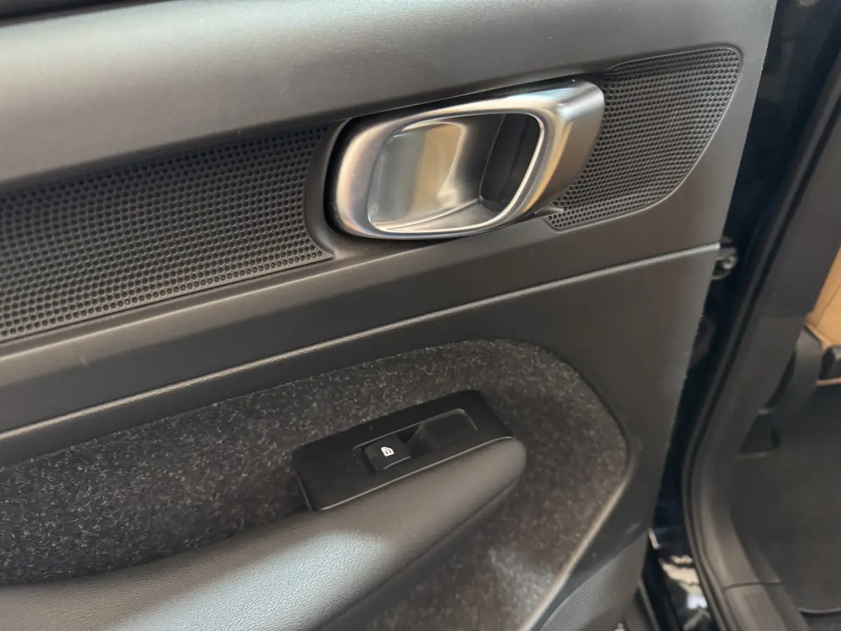 Gros plan sur la poignée intérieure et la commande de verrouillage de la porte côté conducteur du Volvo XC40 noir.