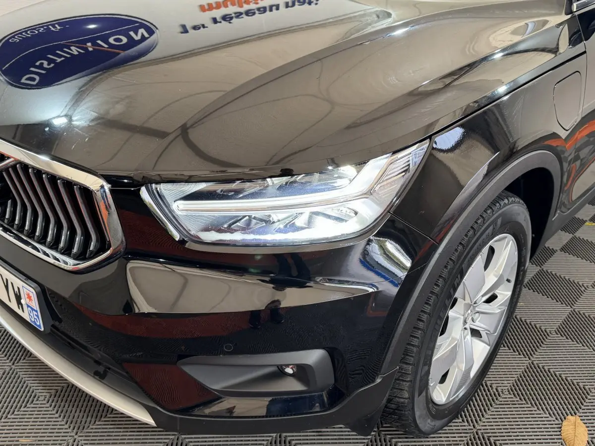 Gros plan sur l'avant droit noir brillant du Volvo XC40 Recharge T5 avec phare LED et jante alu visible.