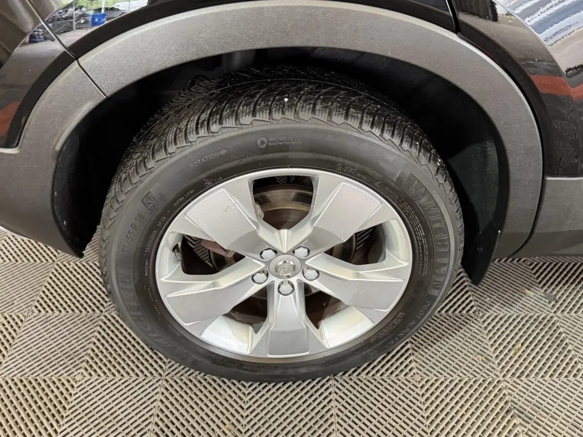 Gros plan sur la roue avant gauche avec jante argentée et pneu Michelin du Volvo XC40 noir Recharge T5 262 DCT7 Inscription.