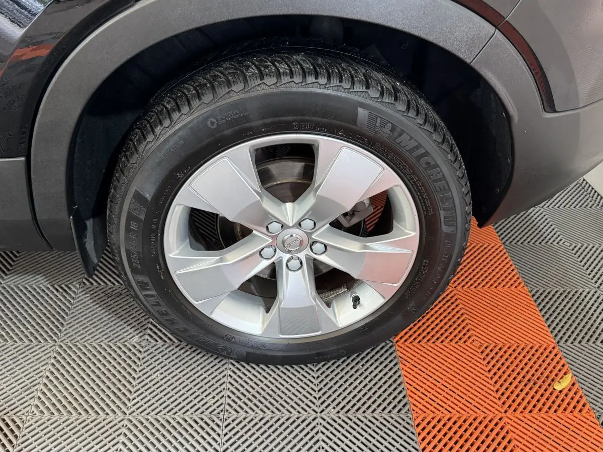 Gros plan sur la roue avant droite avec jante argentée du Volvo XC40 noir Recharge T5 Inscription 2021.