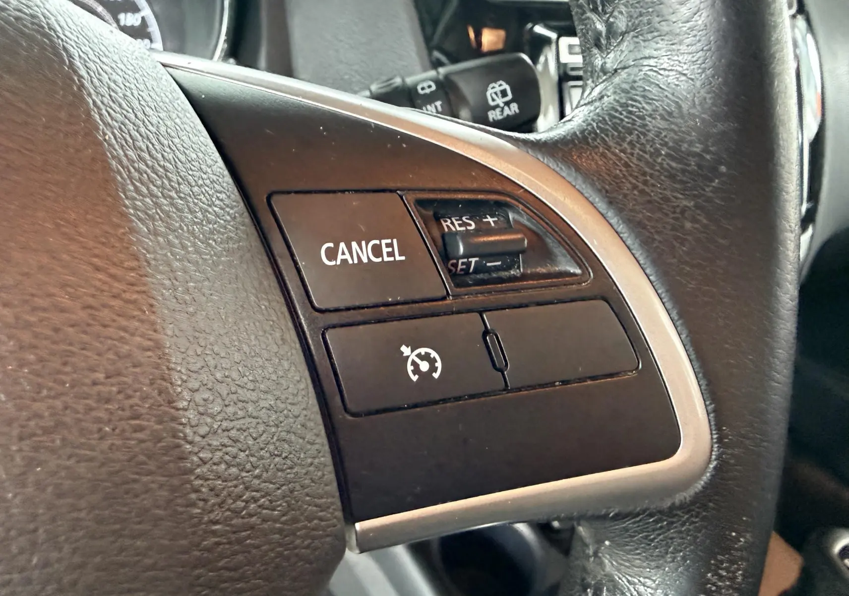 Gros plan sur les commandes de régulateur de vitesse sur le volant en cuir noir du Mitsubishi ASX gris 2015.