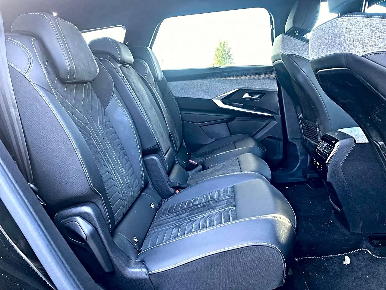Vue latérale droite de l'intérieur arrière du Peugeot 5008 Hybrid 145 GT avec sièges en cuir noir et tissu gris.