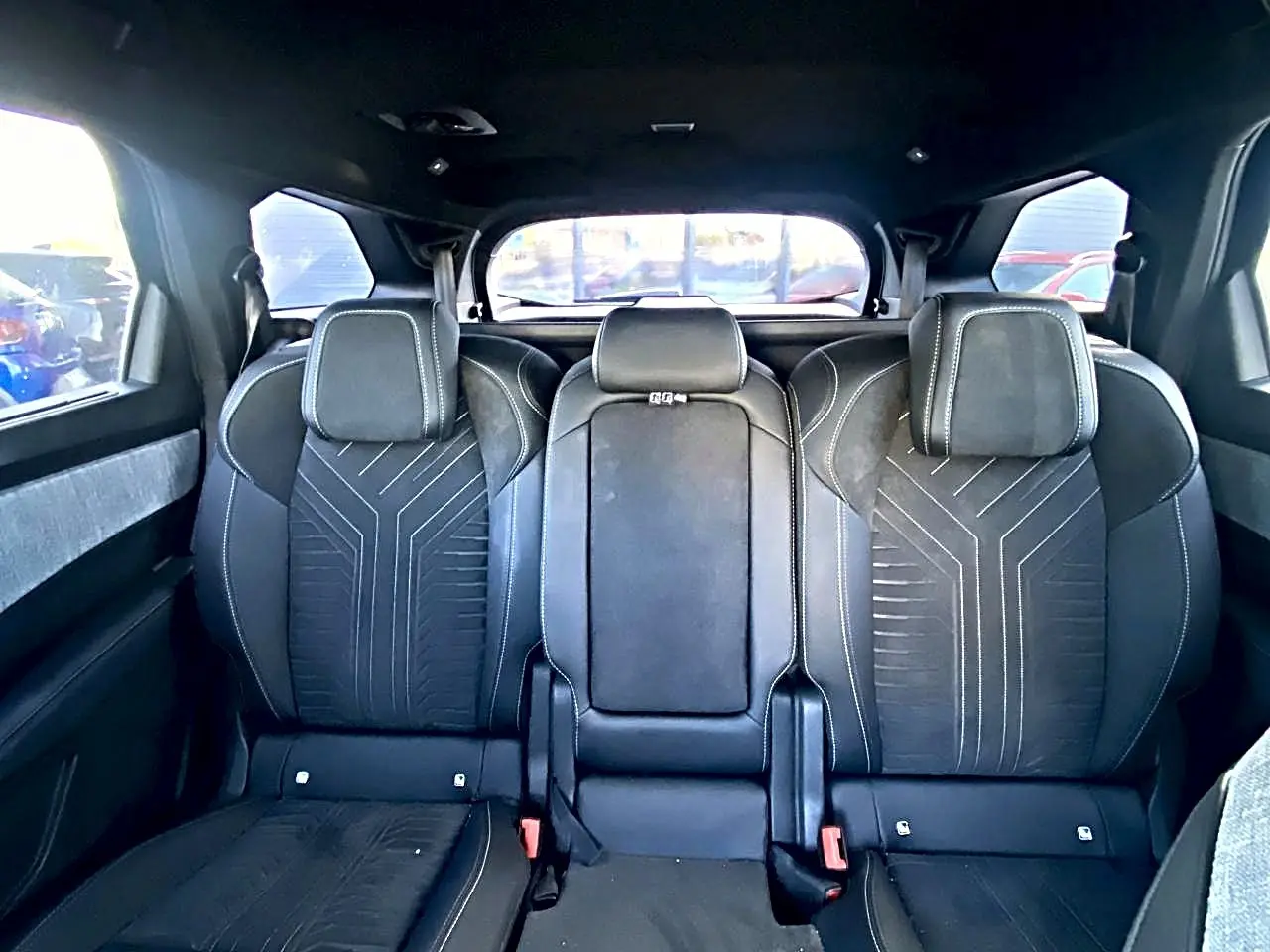 Vue arrière intérieure sur les sièges noirs du rang 2 du Peugeot 5008 Hybrid 145 GT avec appuis-tête et surpiqûres.