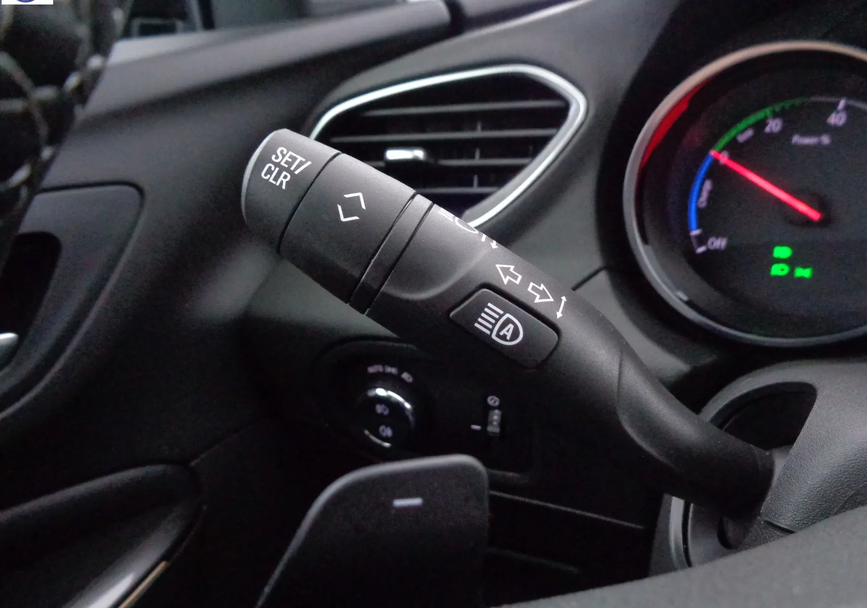Gros plan sur la commande de clignotants et régulateur de vitesse dans l'habitacle noir de l'Opel Grandland X hybride.