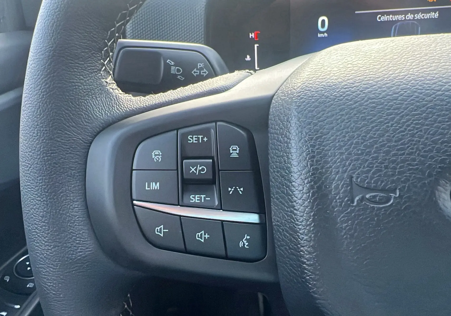 Gros plan sur les commandes au volant côté gauche du Ford Ranger 2025 noir shadow, affichage digital en arrière-plan.