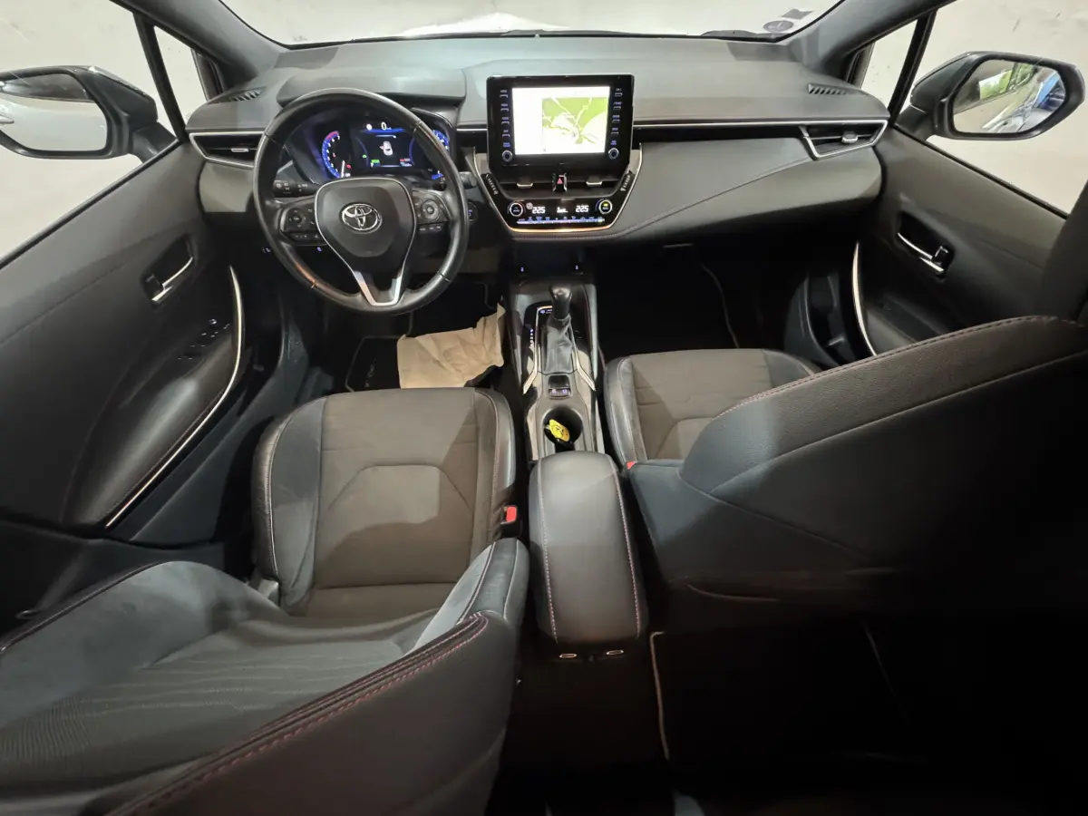 Vue intérieure avant de la Toyota Corolla Hybride 122h Collection 2021, tableau de bord avec écran tactile et volant cuir noir.