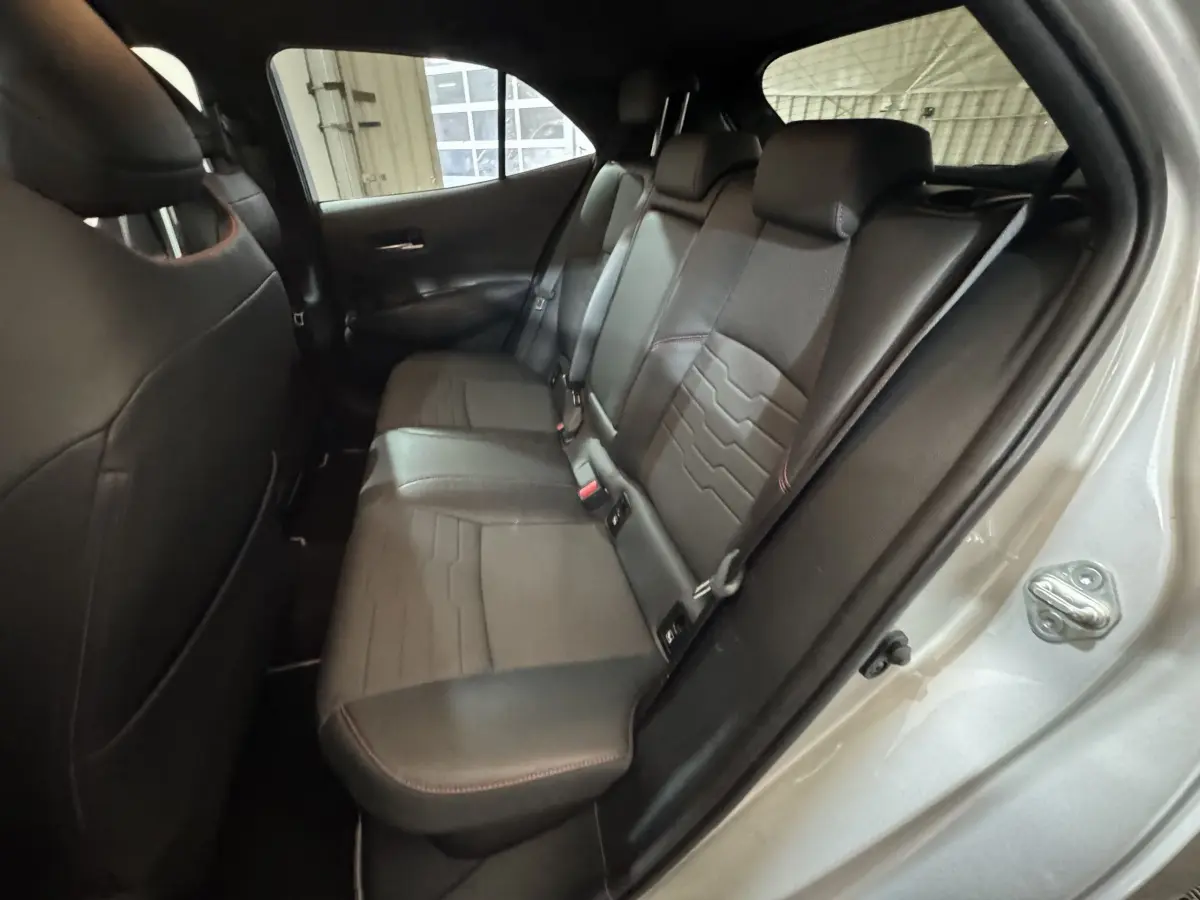 Vue intérieure côté droit des sièges arrière en cuir noir avec surpiqûres rouges d'une Toyota Corolla Hybride 2021 gris clair.