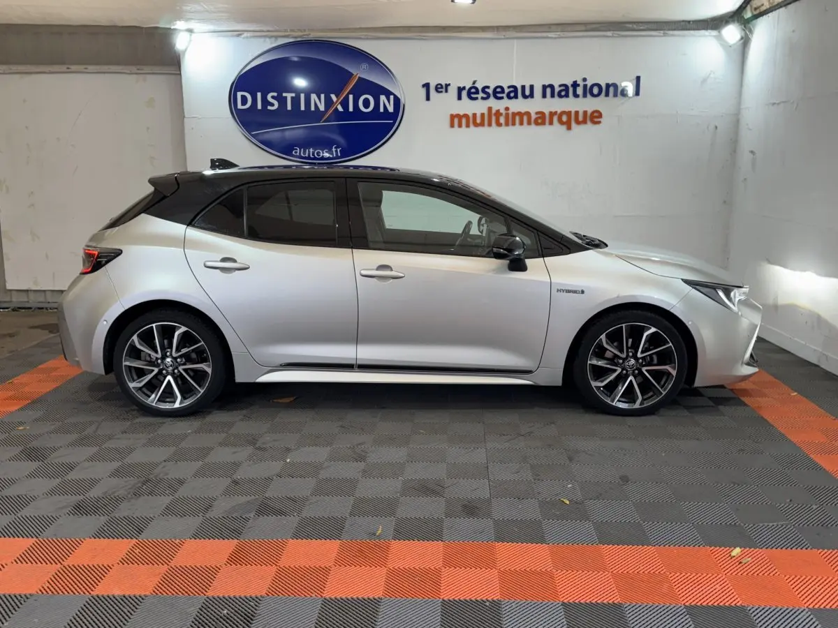 Profil droit d'une Toyota Corolla Hybride gris clair 2021, avec toit noir et jantes alliage distinctives.