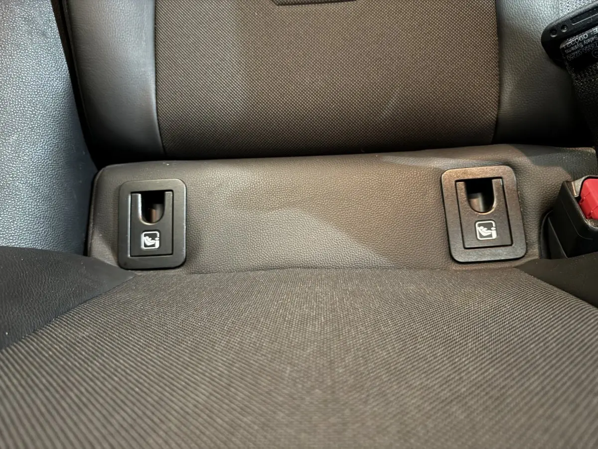 Gros plan sur les fixations Isofix noires intégrées à la banquette arrière grise de la Toyota Corolla Hybride 122h Collection.