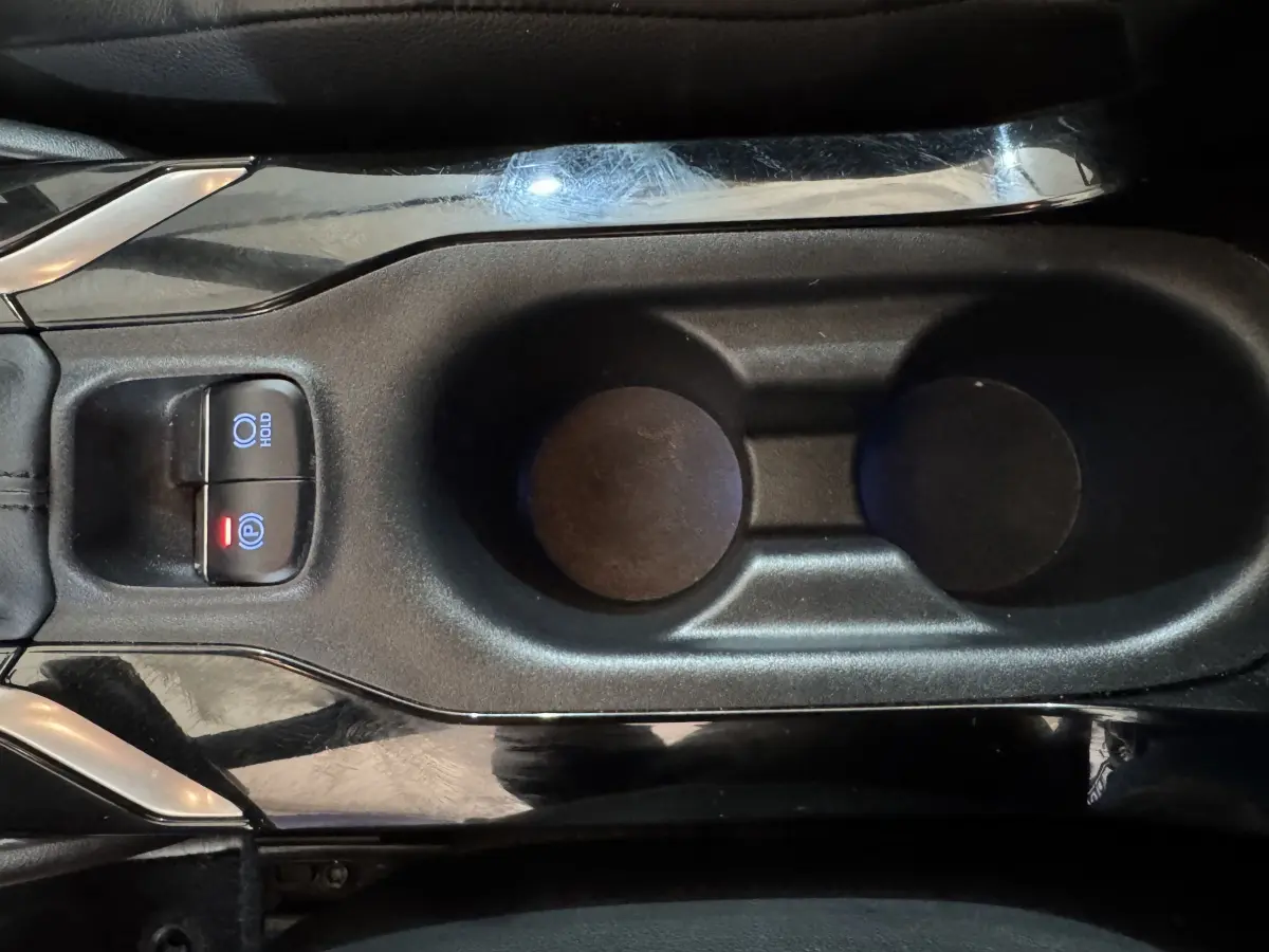 Vue rapprochée de la console centrale noire de la Toyota Corolla Hybride 122h avec boutons frein à main électrique et hold.