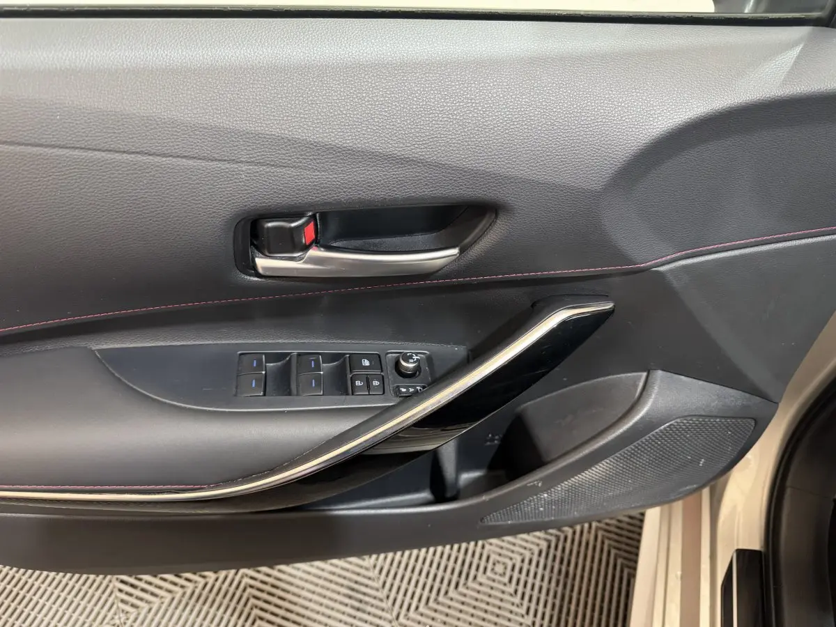 Gros plan sur la porte intérieure côté conducteur de la Toyota Corolla Hybride 122h Collection gris clair, avec commandes électriques.