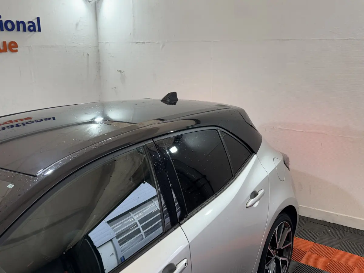 Vue 3/4 arrière droite d'une Toyota Corolla Hybride 122h Collection gris clair avec toit noir et vitres teintées.