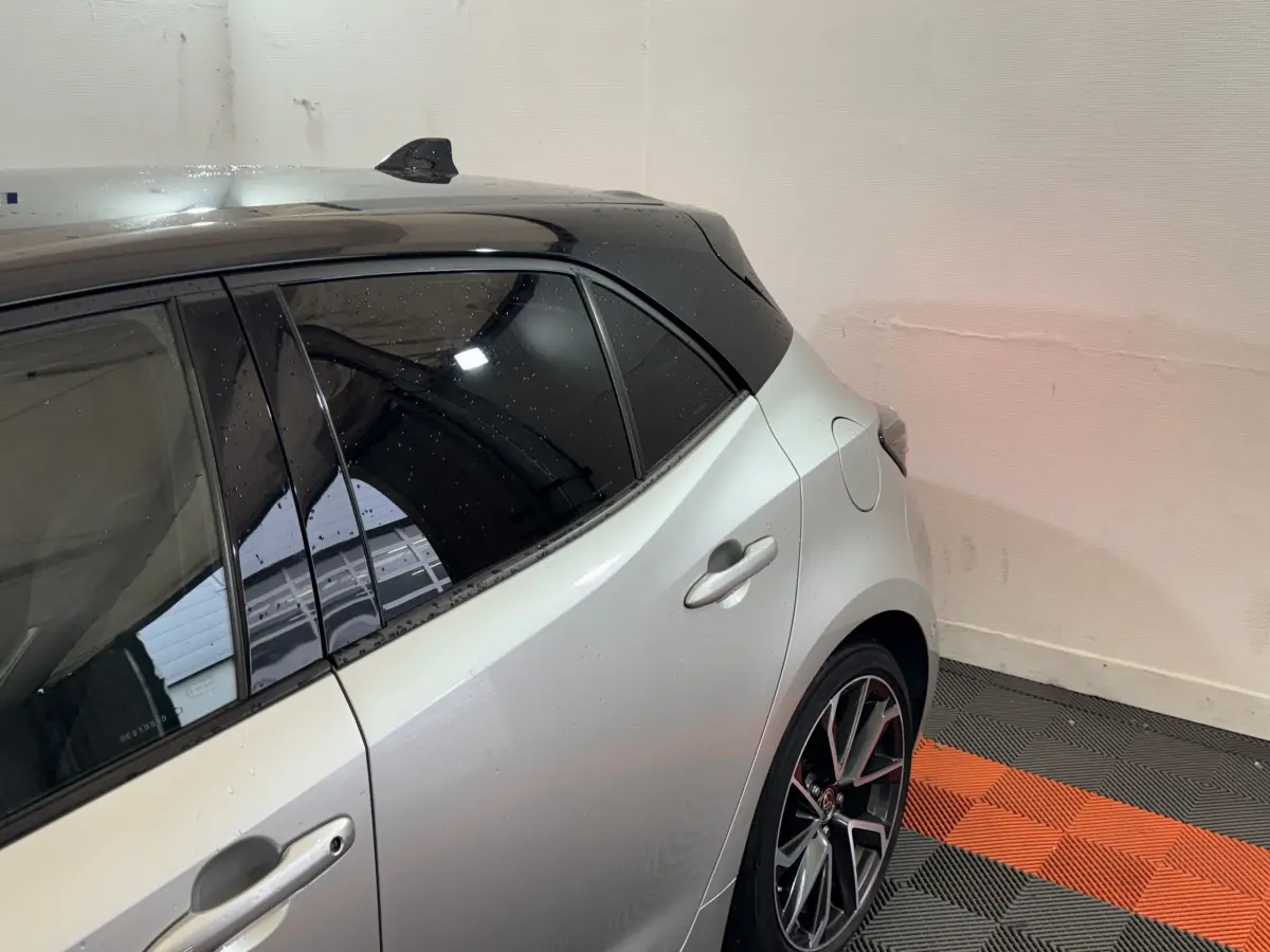 Vue arrière côté droit d'une Toyota Corolla Hybride 122h Collection gris clair avec toit noir et jantes alliage.