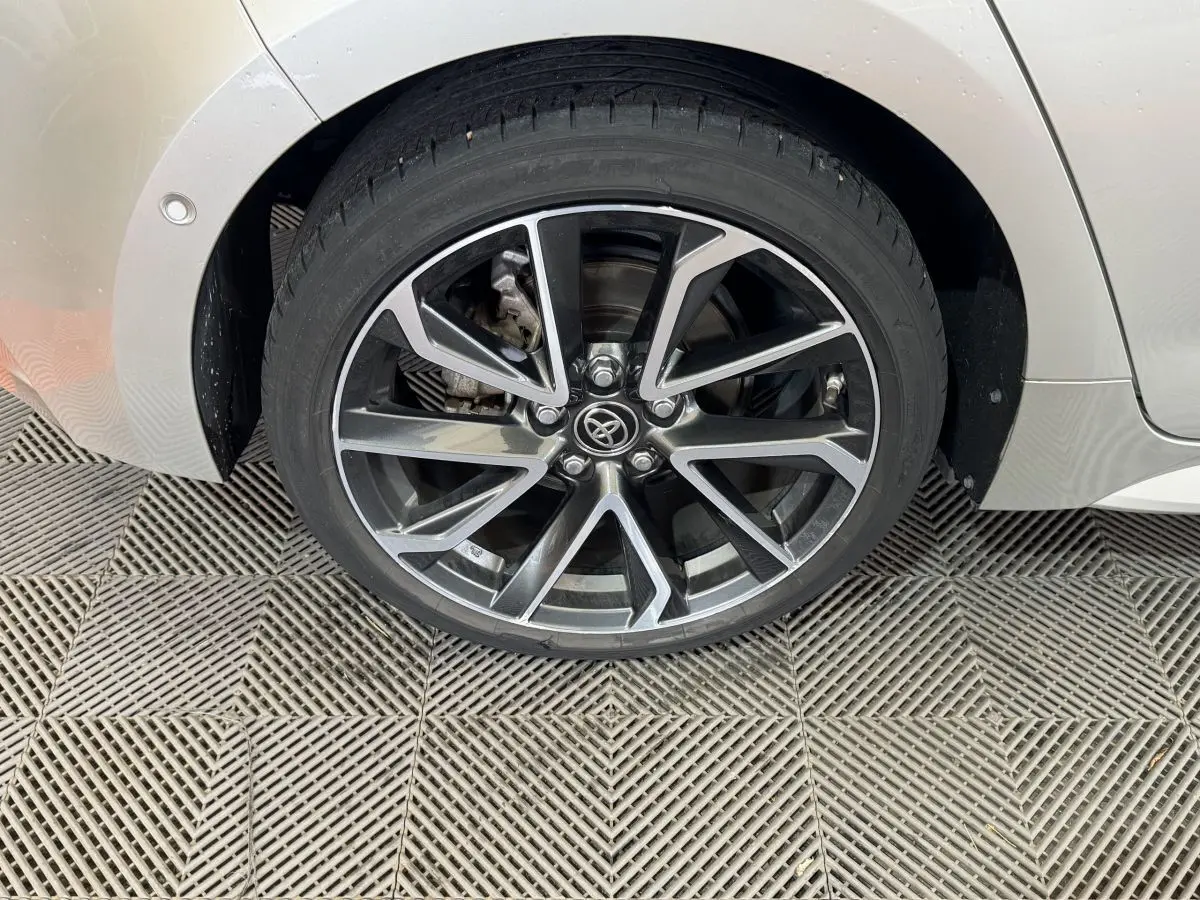 Gros plan sur la roue arrière droite gris clair d'une Toyota Corolla Hybride 122h Collection avec jante alliage noire et argent.