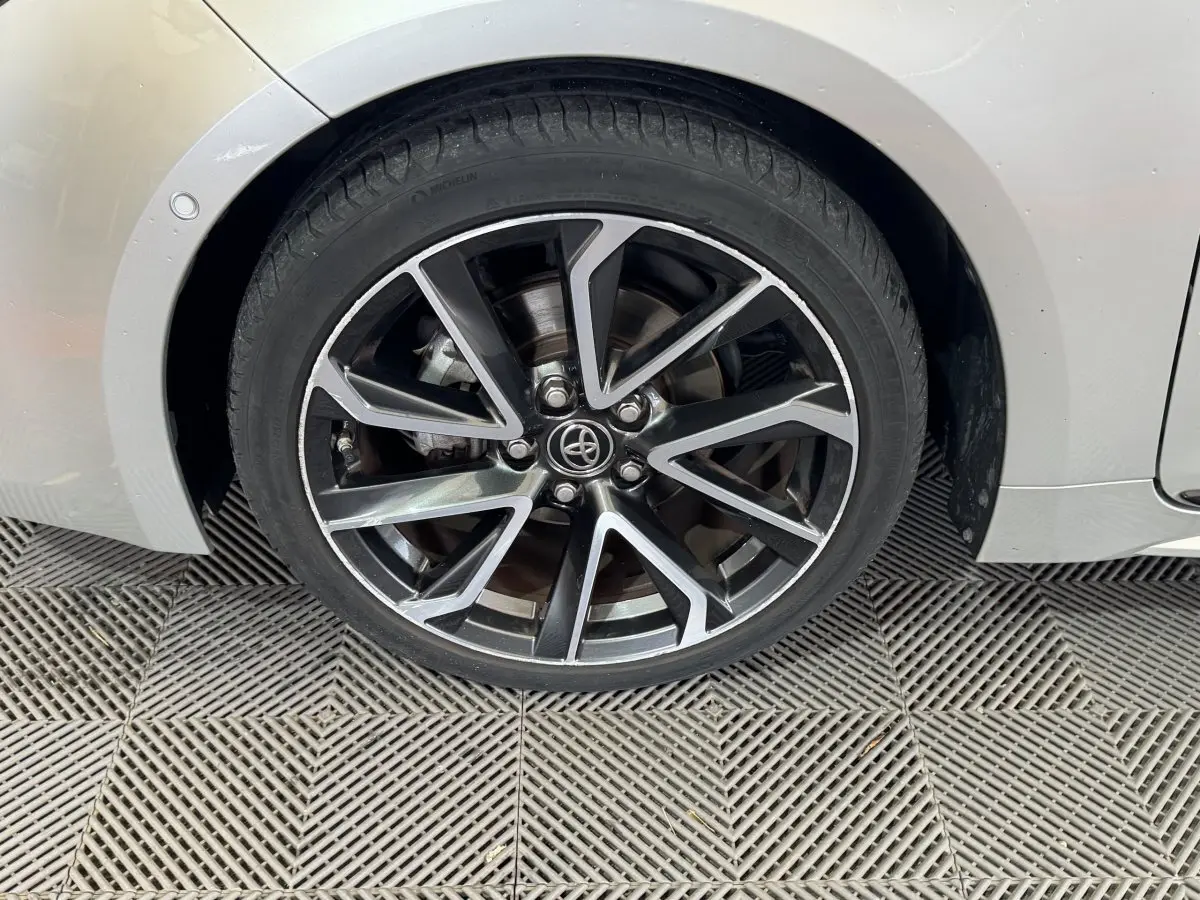 Gros plan sur la roue avant droite gris clair de la Toyota Corolla Hybride 122h Collection avec jante alliage noire et argent.