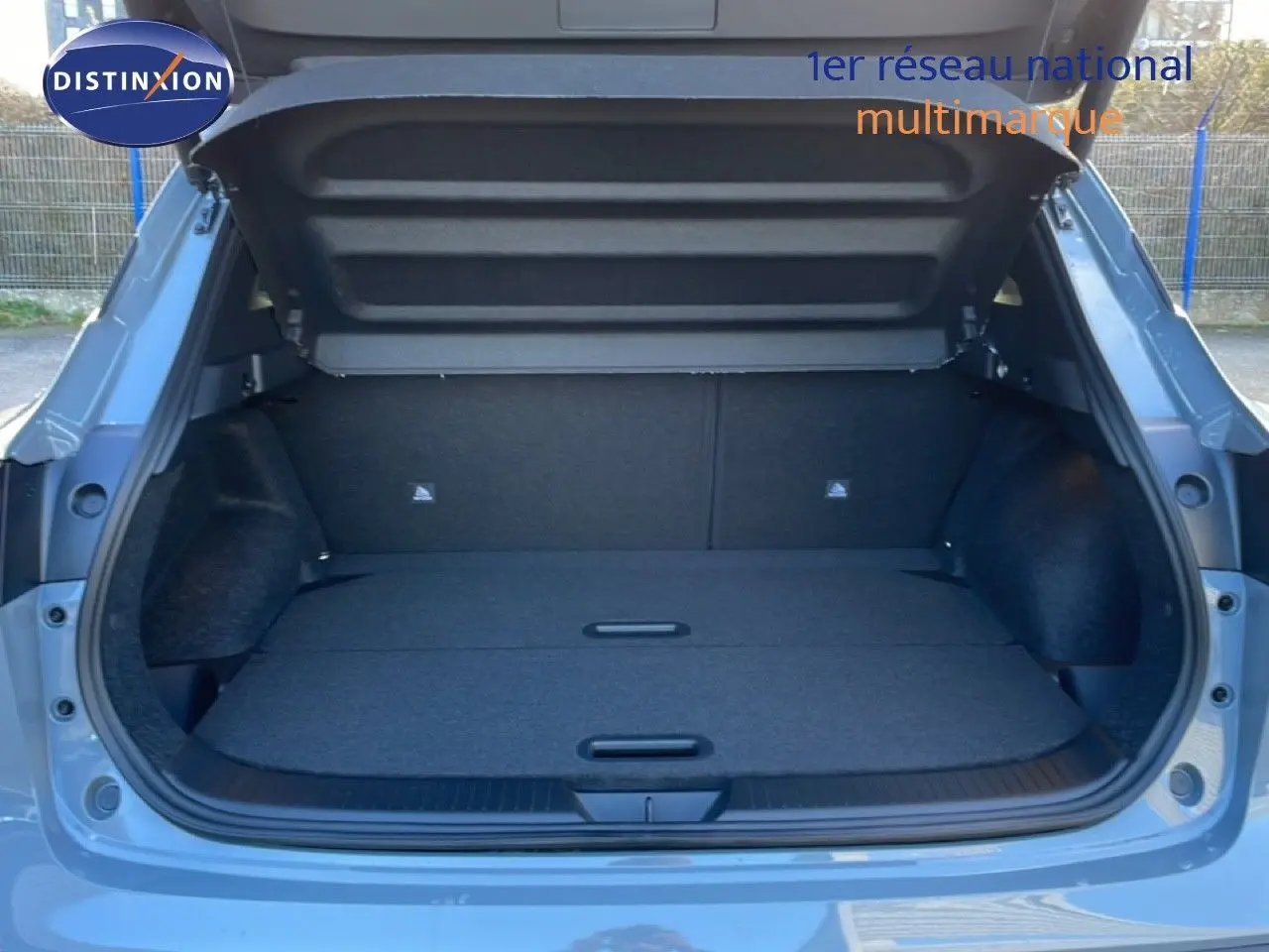 Coffre ouvert vu de l'arrière d'un Nissan Qashqai 2025 gris argile métal, montrant un espace de chargement plat et spacieux.