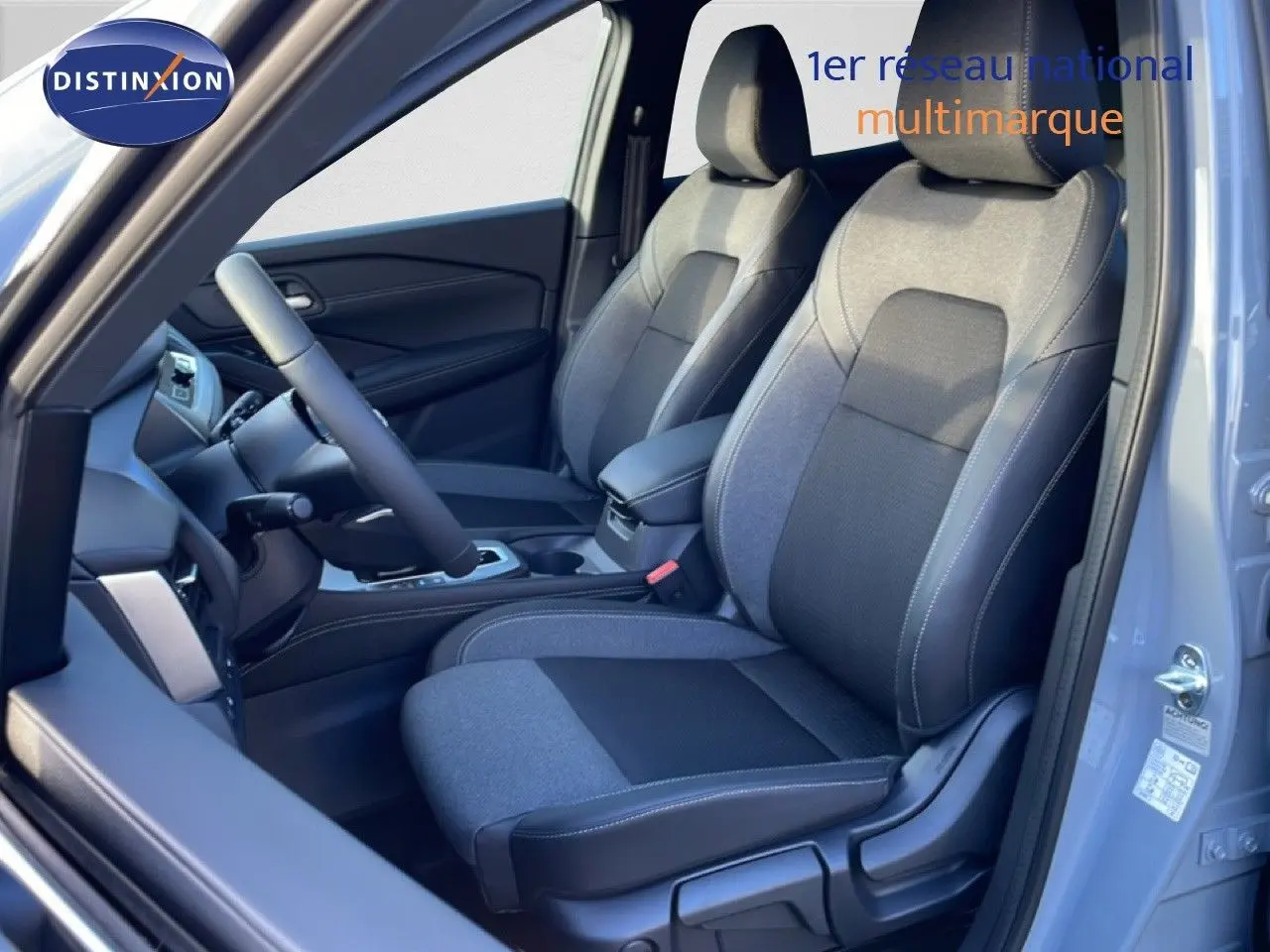 Vue intérieure côté conducteur du Nissan Qashqai 2025 gris argile, mettant en valeur les sièges tissu bi-ton et le tableau de bord.