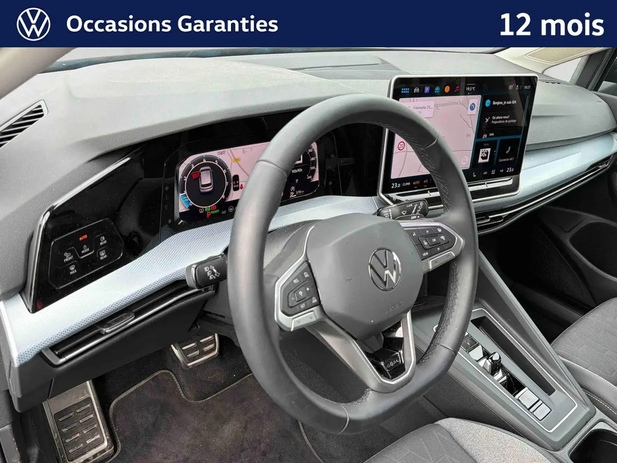 Vue intérieure du poste de conduite de la Volkswagen Golf 1.5 eTSI 150 DSG7 2025, avec volant multifonction et écran tactile central.