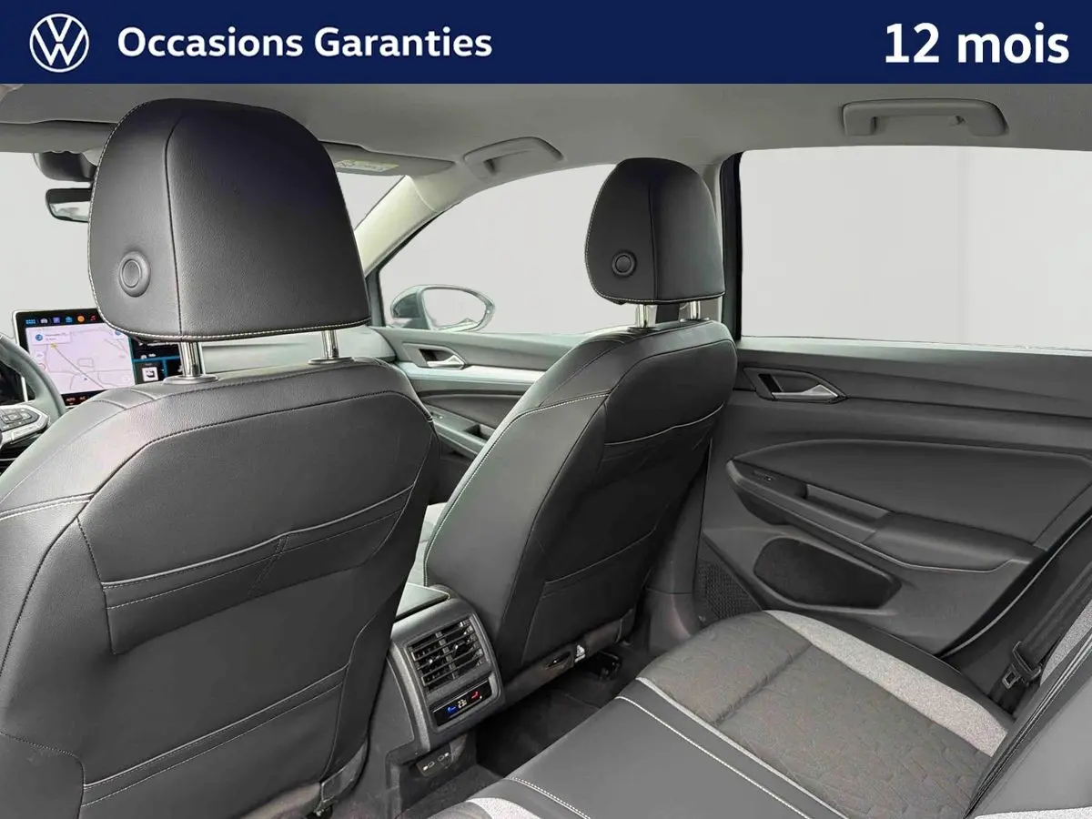 Vue intérieure arrière droite de la Volkswagen Golf gris, montrant les sièges en cuir noir et la console avec aérateurs et commandes climatiques.