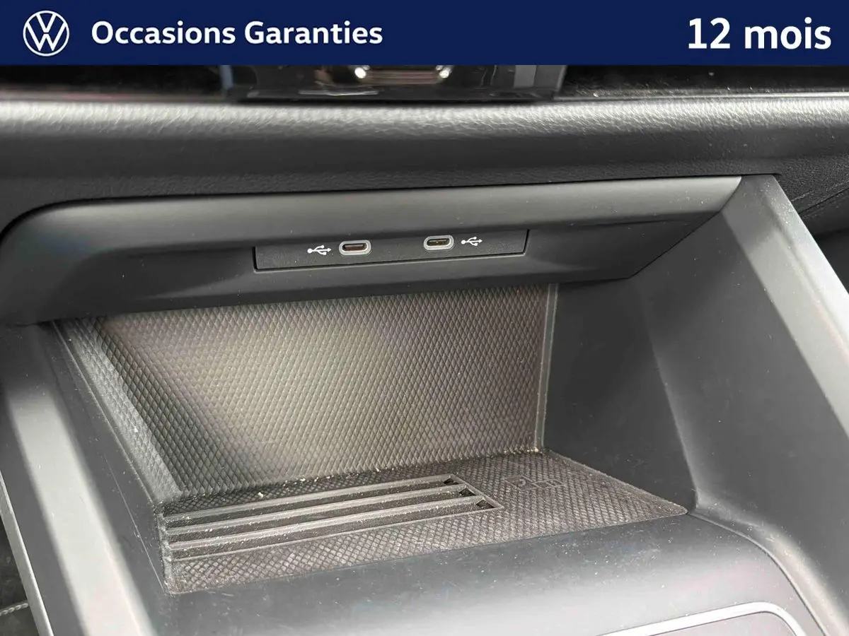 Gros plan sur la console centrale d'une Volkswagen Golf grise, montrant deux ports USB-C et un espace de rangement.