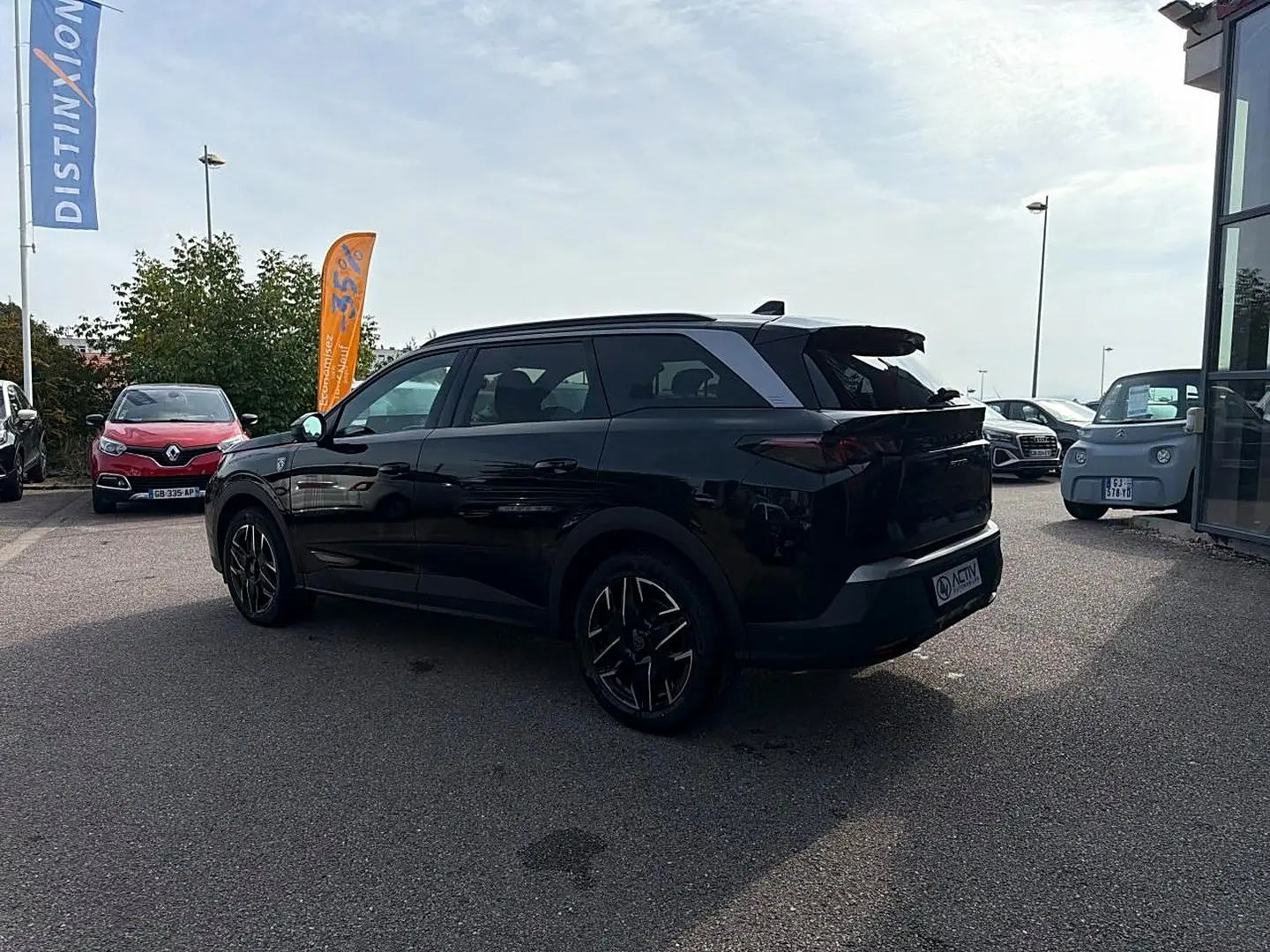 Peugeot 5008 Hybrid noir vue 3/4 arrière droit, jantes alu et becquet arrière visibles en extérieur.