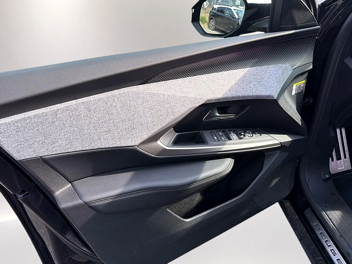 Intérieur côté conducteur du Peugeot 5008 Hybrid 145 GT e-dcs6 2025, porte ouverte avec habillage tissu gris et cuir noir.
